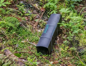 Black tunnel rat trap on the ground in an area with lots of vegetation